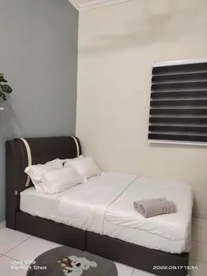 a bedroom with a bed with white sheets and a window at Homestay Mewah Lumut in Lumut