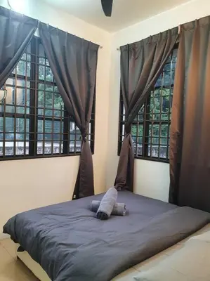 a bed in a bedroom with two windows at 3 Storey Bangalow near Spice Arena & Queensbay Mall in Bayan Lepas