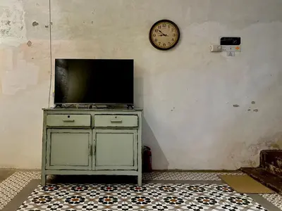 a television on a cabinet with a clock on the wall at (New) Eternal Granpa’s heritage(UNESCO)/11pax/3BR in George Town