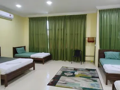 a room with three beds and green curtains at Fadlim Homestay in Padang Serai