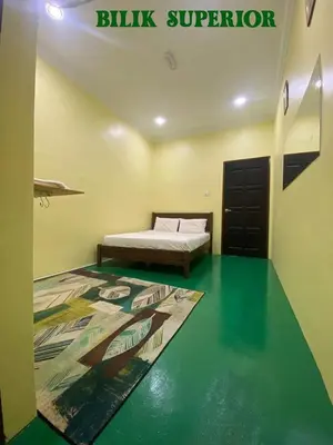 a bedroom with a bed and a green floor at Fadlim Homestay in Padang Serai