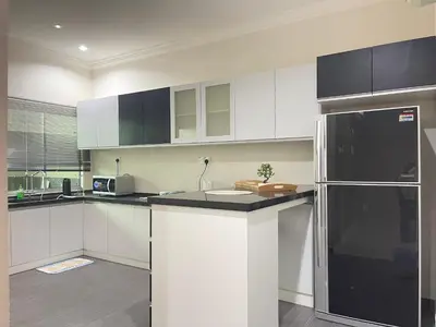 a kitchen with white cabinets and a black refrigerator at Art Homestay 4 Bedrooms House by Mr Homestay in Teluk Intan