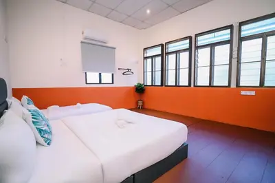 a bedroom with two beds and orange and white walls at Swing & Pillows - 75 Chulia St, Georgetown Penang in George Town