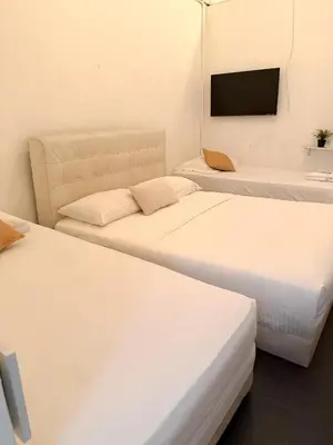 three beds in a room with a tv on the wall at Goodnight Homestay in George Town