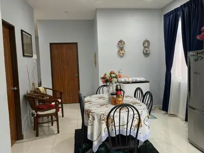 a dining room with a table and chairs and a kitchen at Homestay Warisan Abang Tam in Kepala Batas