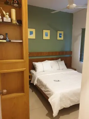 a bedroom with a bed with white sheets and green walls at Chor Residence Homestay in Ipoh