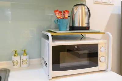 a microwave oven with a coffee pot on top of it at Deluxe Studio/Gurney/Mansion One in George Town