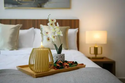a tray with a candle and flowers on a bed at Deluxe Studio/Gurney/Mansion One in George Town