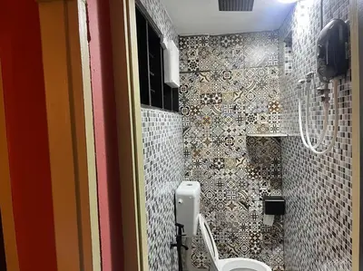 a bathroom with a toilet and a tiled wall at Wi-Fi 100MB Free Ipoh Happy Big House SemiD TH24 16 pax in Ipoh