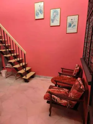 a room with a red wall with stairs and chairs at Wi-Fi 100MB Free Ipoh Happy Big House SemiD TH24 16 pax in Ipoh