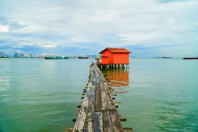 a dock with a red house in the water at Quint Residence, Georgetown - Rustic Heritage Guesthouse by ALV in George Town