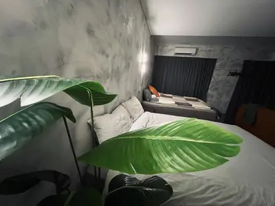 a bedroom with a bed with a large green plant at The Ash Ipoh - Family Suite in Ipoh