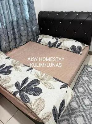 a bed with a black headboard and pillows on it at AISY HOMESTAY KULIM/LUNAS in Kulim
