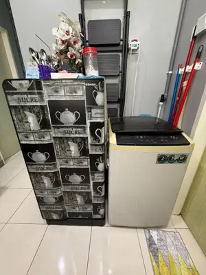 a refrigerator next to a table with photographs on it at AISY HOMESTAY KULIM/LUNAS in Kulim