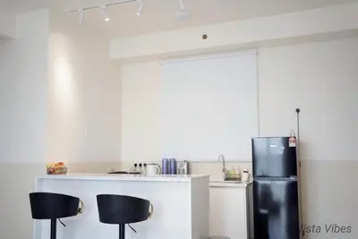 a kitchen with a black refrigerator and two black stools at Urban Suites Homestay by Vista Vibes in Jelutong