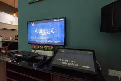 a laptop computer sitting on a desk with a television at Karaoke,XBox,Foosball,Billiard,Air Hockey,Ping Pong & Board Games in George Town