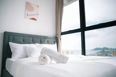 a white bed with a towel on it with a window at NEW Infinity Pool Seaview 3Bedrooms 2Carparks 262 in Jelutong