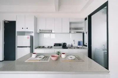 a white kitchen with two plates on a counter at NEW Infinity Pool Seaview 3Bedrooms 2Carparks 262 in Jelutong