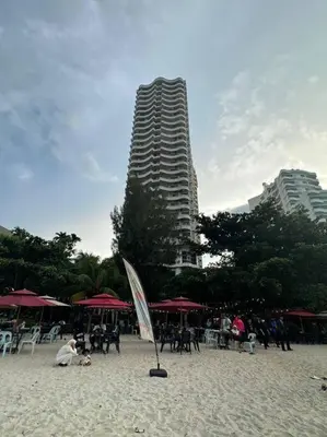 a beach with tables and chairs and a tall building at Rainbow Paradise Homestay @ Tanjung Bungah by Landmark in Tanjung Bungah