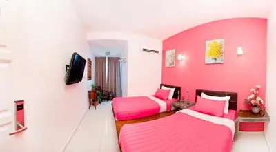 a pink room with two beds and a tv at Hotel O Vince Villa in Bukit Mertajam
