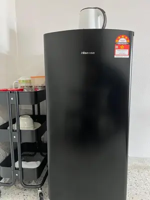a black refrigerator sitting next to a shelf at Naura Roomstay in Sungai Petani