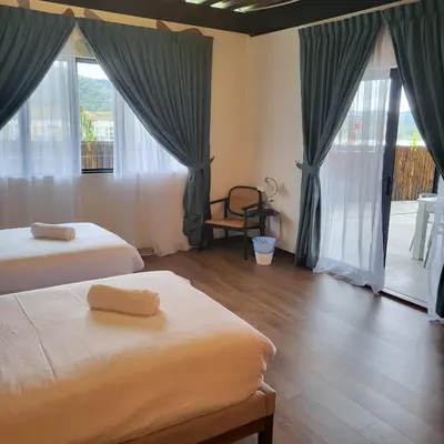 a bedroom with two beds and large windows at kMah@SomerMansion in Tanah Rata