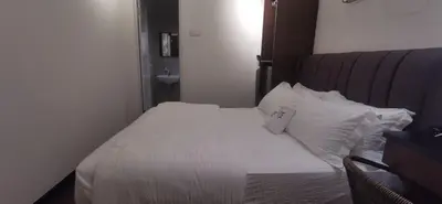 a bedroom with a bed with white sheets and pillows at TREASURE HUNTER At Heritage Georgetown in George Town