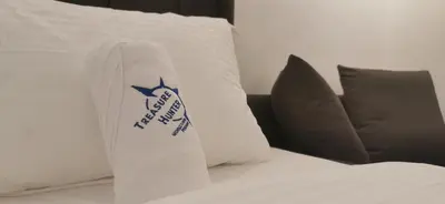 a bed with a pillow with a sign on it at TREASURE HUNTER At Heritage Georgetown in George Town