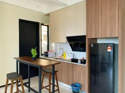 a kitchen with a black refrigerator and a table at Jovial Modern&Stylish `UrbanSuites in Jelutong