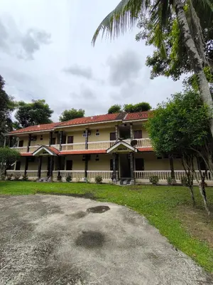 a building with a palm tree in front of it at Hotel O Rumah Rehat Awana in Kampong Nanas