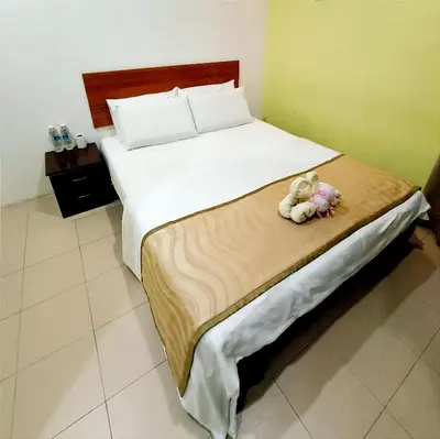 a bed with two stuffed animals sitting on it at Hotel O Rumah Rehat Awana in Kampong Nanas