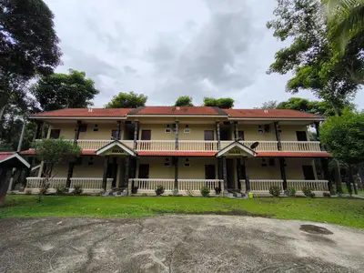 a large yellow house with a red roof at Hotel O Rumah Rehat Awana in Kampong Nanas