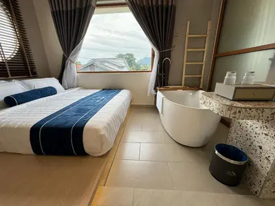a bedroom with a bed and a tub and a window at Muzi Boutique Hotel in Ipoh