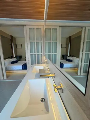a bathroom with a sink and a mirror with two beds at Muzi Boutique Hotel in Ipoh