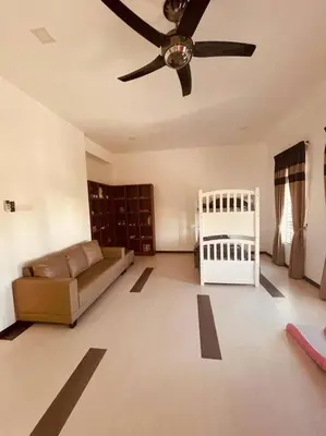 a living room with a ceiling fan and a crib at Maxwell Merpati Taiping Homestay in Kamunting