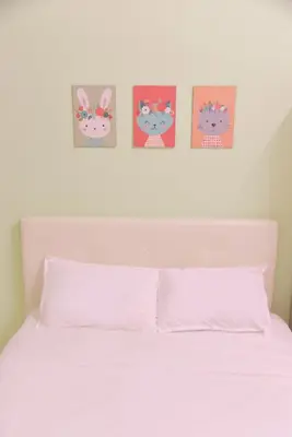 a white bed with four hello kitty pictures above it at The Karaoke Homes Ipoh, Oldtown in Ipoh