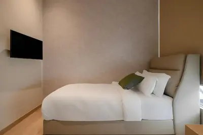 a bedroom with a white bed and a television at La Vie Hotel Juru in Simpang Ampat