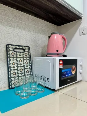 a microwave with glasses and a pink pot on top at MyStay IPOH Manhattan waterpark in Ipoh