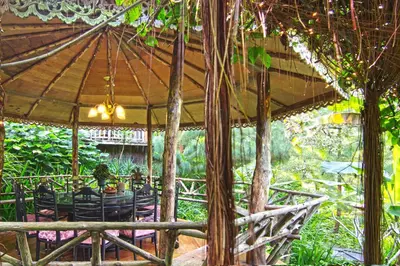 a patio with a table and chairs under an umbrella at Fig Tree Hills Resort (\u82b1\u679c\u5c71\u5ea6\u5047\u6751) in Bayan Lepas