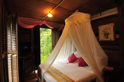 a bedroom with a canopy bed with a window at Fig Tree Hills Resort (\u82b1\u679c\u5c71\u5ea6\u5047\u6751) in Bayan Lepas