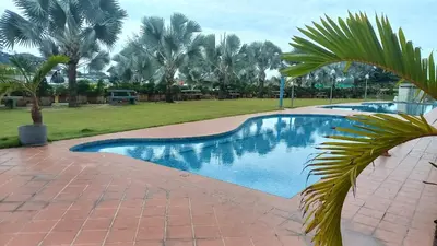 a swimming pool in a yard with palm trees at Laguna Apartment 2, Marina Island Homestay in Kampong Batu Gajah