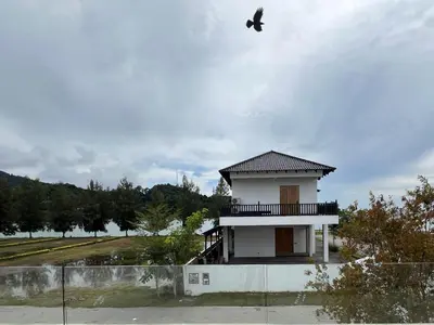 a small white building with a bird flying in the sky at Bichrome Marina Island Private Villa Pangkor Lumut in Lumut