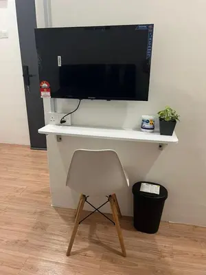 a desk with a chair and a television on a wall at KIWI INN in Taiping