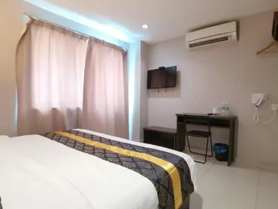 a hotel room with a bed and a desk and a television at Star Bay Hotel in Lumut
