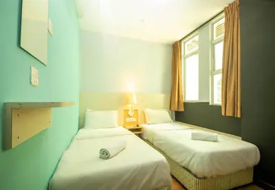 two beds in a room with blue walls and windows at JQ Station Eight Inn in Ipoh