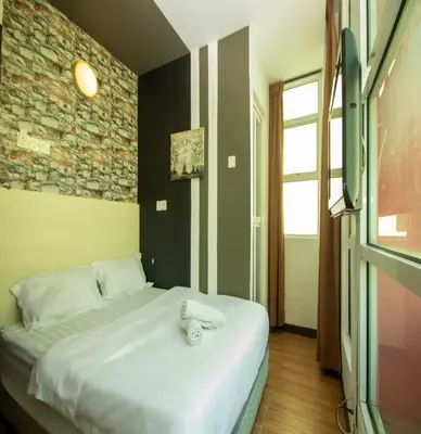 a bed in a room with a brick wall at JQ Station Eight Inn in Ipoh