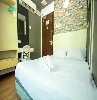 a bedroom with a large white bed and a chair at JQ Station Eight Inn in Ipoh