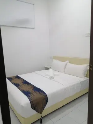 a bed with white sheets and a brown blanket on it at SKYN SMART HOME in Ipoh