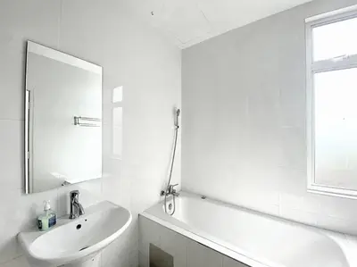 a white bathroom with a sink and a mirror at Shamrock Breeze Villa: Coastal Haven for 29 Guests in Batu Ferringhi