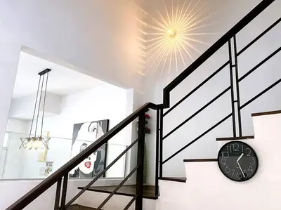 a clock on a wall next to a staircase at Shamrock Breeze Villa 2: Coastal Haven for 25 Guests in Batu Ferringhi